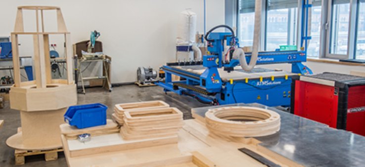 Na zdjęciu widać warsztat stolarski ze stołem i  maszynami do obróbki drewna.