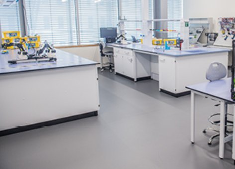 Na zdjęciu widać pomieszczenie z białymi stołami i szafkami oraz sprzętem badawczym