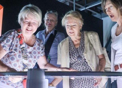 Troje starszych osób nad eksponatem