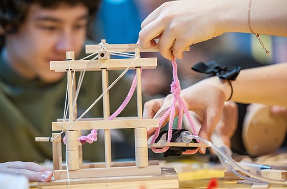 Dwie dłonie, które majstrują coś z drewnianą konstrukcją