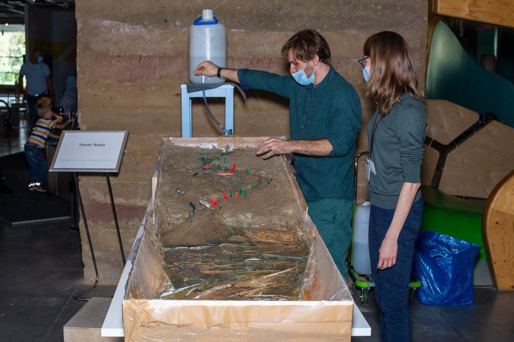 Dwoje dorosłych nad długim korytem wypełnionym betonem