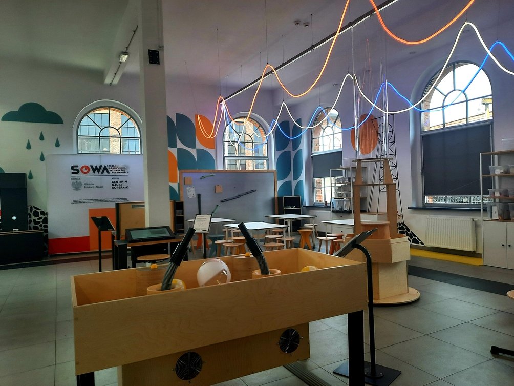Wnętrze strefy SOWA, pod sufitem są kolorowe światła, na dole widać eksponaty.