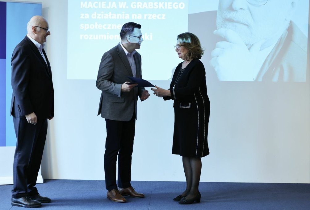 ALT do foty: Dyrektor Robert Firmhofer odbiera z rąk marszałek Senatu Małgorzaty Kidawy-Błońskiej, córki profesora Macieja Grabskiego, przyznawane przez FNP Wyróżnienie jego imienia za działania na rzecz społecznego rozumienia nauki w siedzibie Fundacji Batorego w Warszawie. Obok prezes zarządu Fundacji na rzecz Nauki Polskiej stoi Maciej Żylicz.