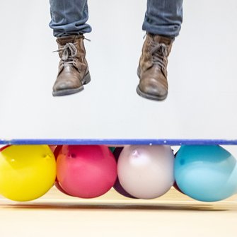 Kolorowe balony a nad nimi nogi podskakującego człowieka