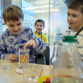 Grupka dzieci przy stole z różnymi pojemnikami 