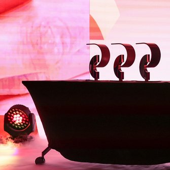  Trzy statuetki Nagrody Przewroty ustawione na czarnym stole, podświetlone światłami scenicznymi.