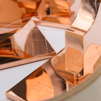 Zbliżenie na błyszczącą podstawę statuetki z napisem „Nagroda Przewroty 2025”.