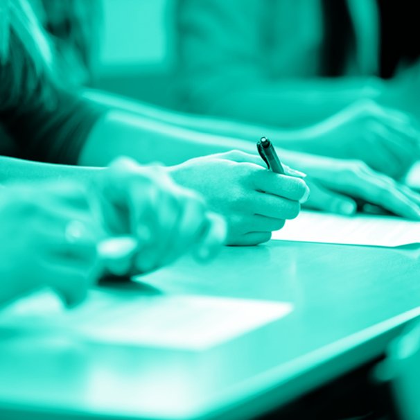 Zdjęcie z niebieskim filtrem, mocno skadrowane, widać dłonie ludzi z długopisami.