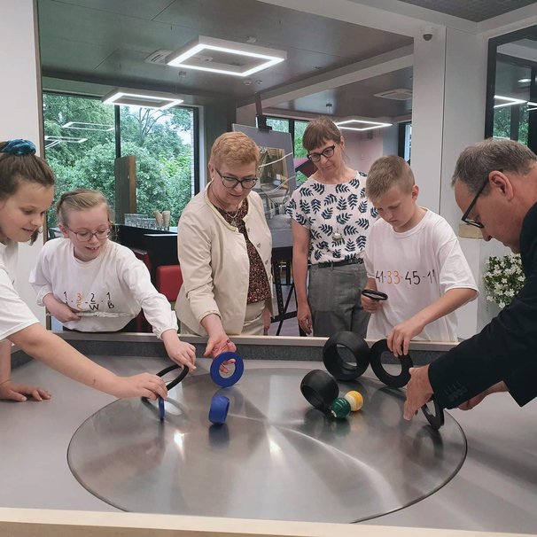 Dorośli i dzieci eksperymentują przy eksponacie "Stolik obrotowy" na wystawie SOWA w Bolesławcu 