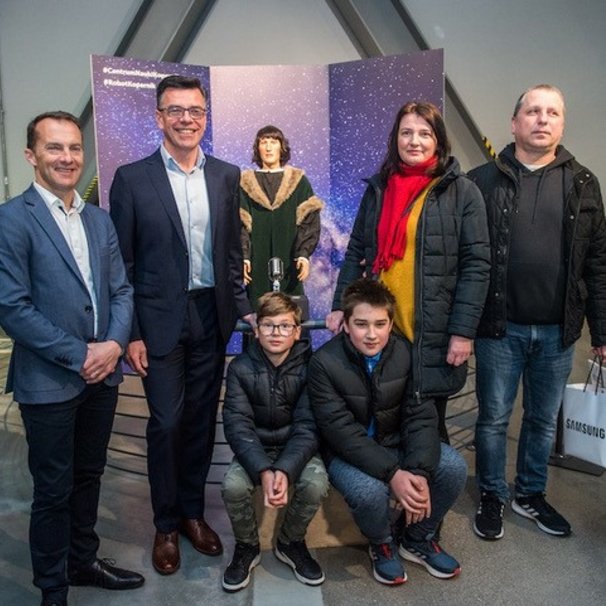  Na zdjęciu widać 12-milionowego gościa Centrum Nauko Kopernik, panią Annę z mężem Rafałem oraz synami Filipem i Adrianem, a także dyrektora Centrum Roberta Firmhofera oraz prezesa @Samsung Electronics Polska – Conora Pierce'a. W tle robot Kopernik. 