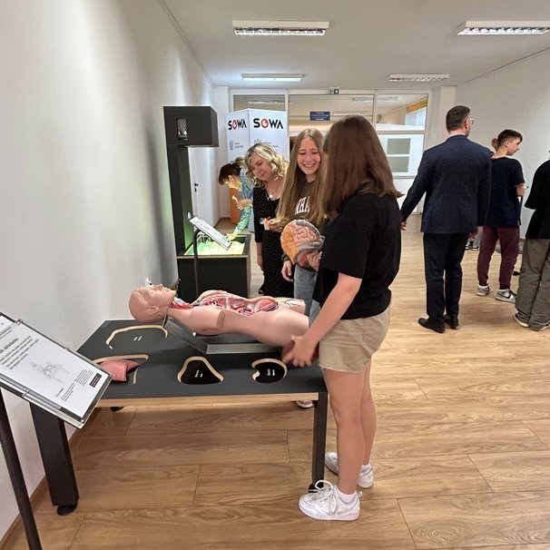 Zwiedzający eksperymentują przy eksponatach. Na perwszym planie widoczny eksponat „Człowiek-układanka”.