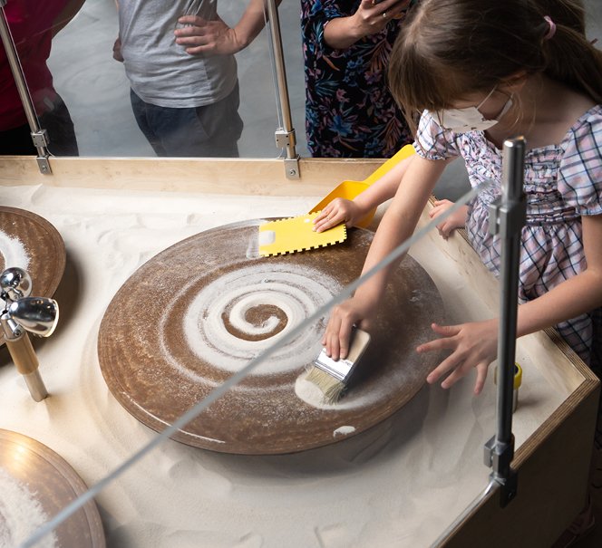 Rysowanie na piasku - dzieci eksperymentują na kręcących się talerzach z piaskiem