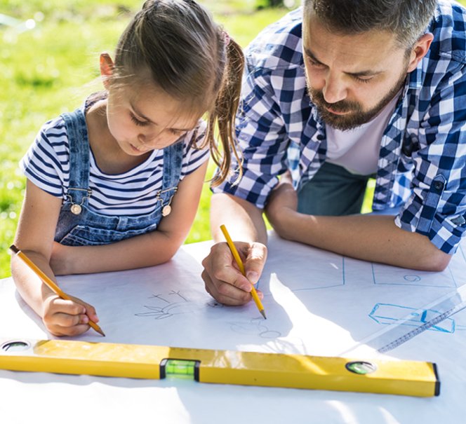 Ojciec i córka rysują w plenerze przy stole, na dużym arkuszu białego papieru rysunek techniczny  