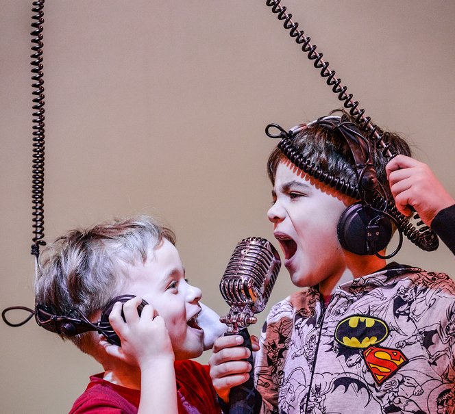 Dwoje dzieci w słuchawkach śpiewających do mikrofonu