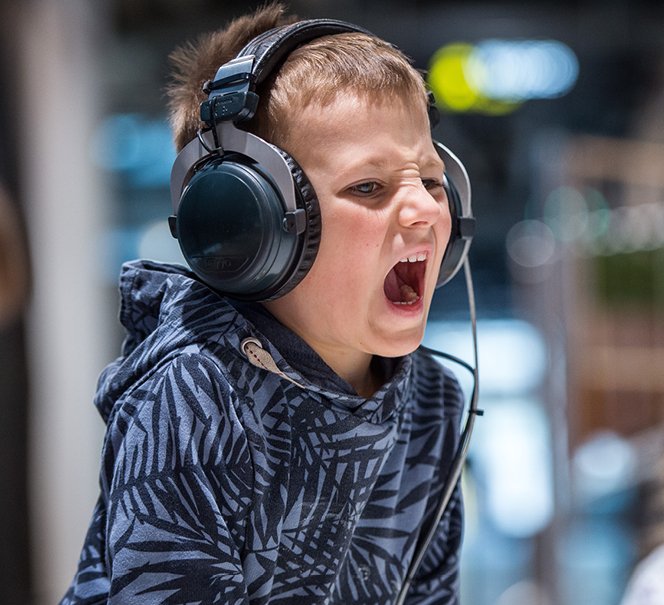 Krzyczący chłopiec ze słuchawkami na uszach