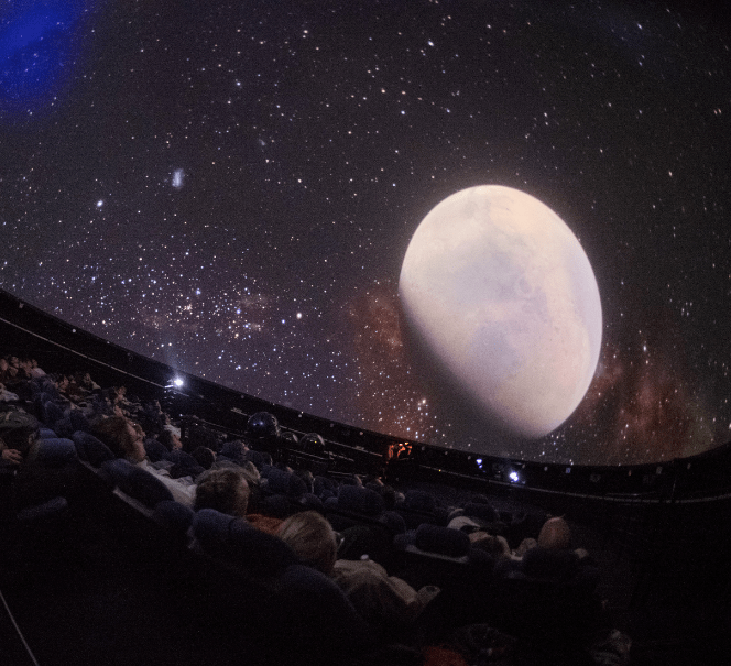 Na kopule planetarium widoczna projekcja księżyca z otaczającymi gwiazdami.