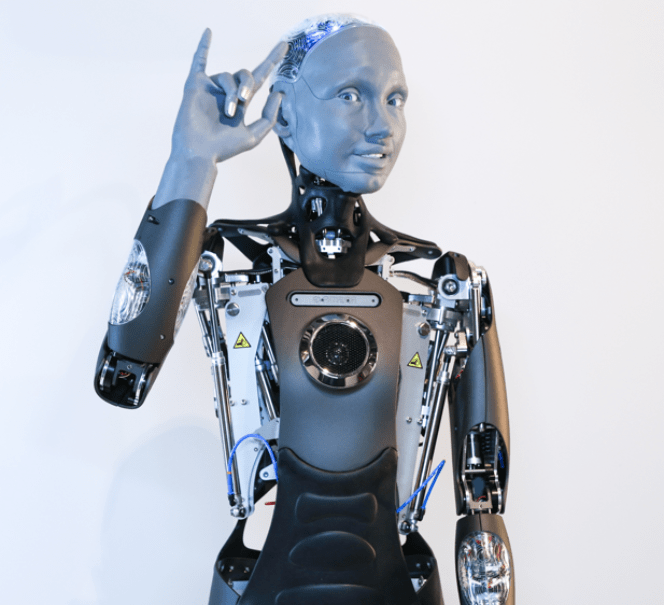 Robot humanoidalny z uniesioną dłonią i odsłoniętym wewnątrz mechanizmem.