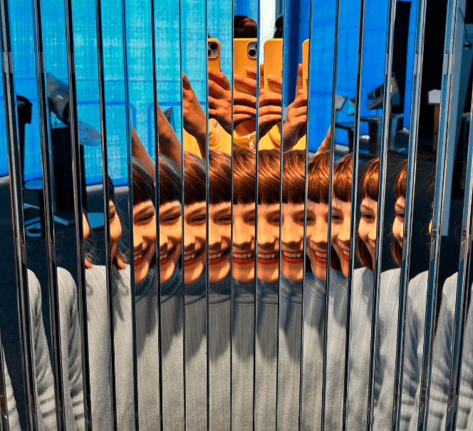 Odbicie twarzy dziecka wielokrotnie powielone w lustrzanym panelu.