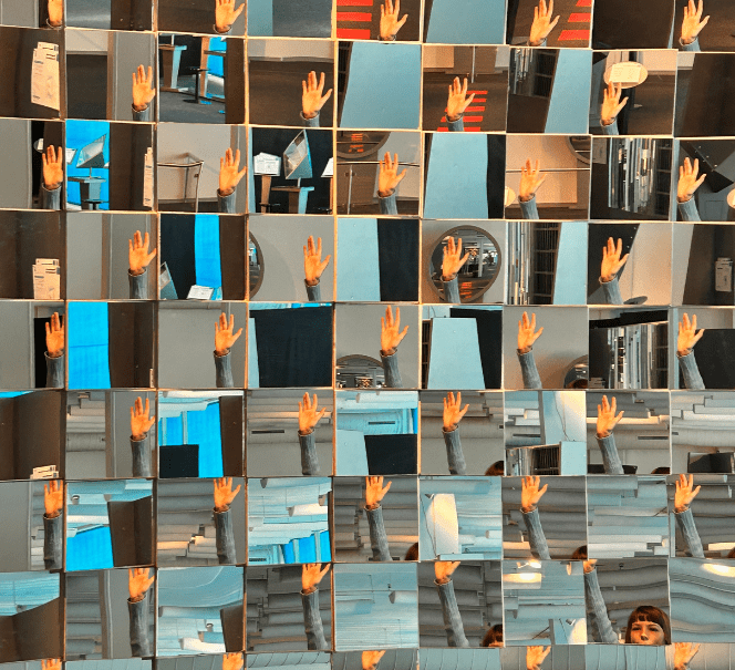 Fragmenty odbić dłoni i twarzy dziecka w mozaice złożonej z wielu małych luster.