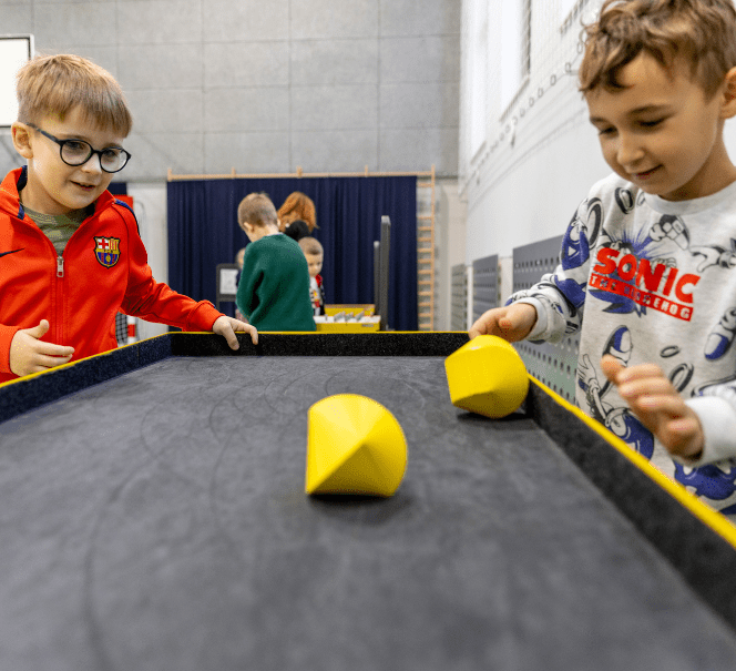 Dwóch małych chłopców przy eksponacie z kolorowymi figurami