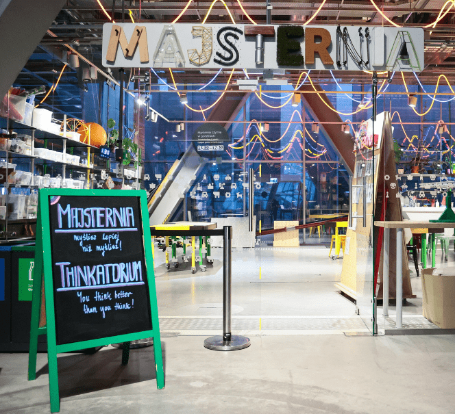 Wejście do Majsterni w Centrum Nauki Kopernik; nad wejściem napis, obok tablica z hasłem „Myślisz lepiej, niż myślisz”.